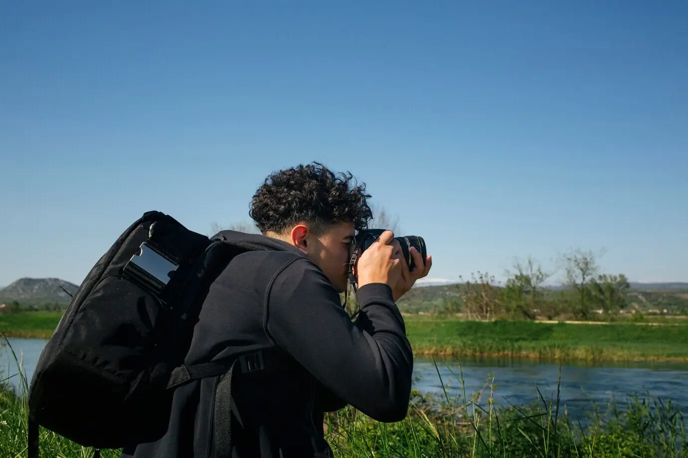 Ein Mann mit Rucksack fotografiert fließendes Wasser.